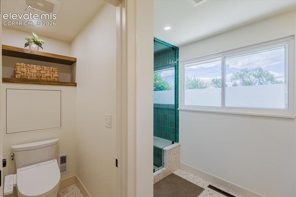 Image 42 of 49: White-tiled bathroom featuring a built-in shower with green subway tile, a