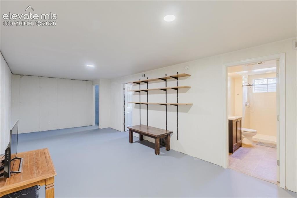 Image 44 of 49: Open-concept room with light gray flooring and white walls, featuring built