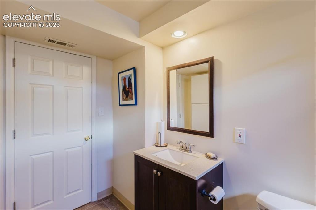 Image 48 of 49: Powder room featuring a dark wood-finish vanity with an integrated sink, ch