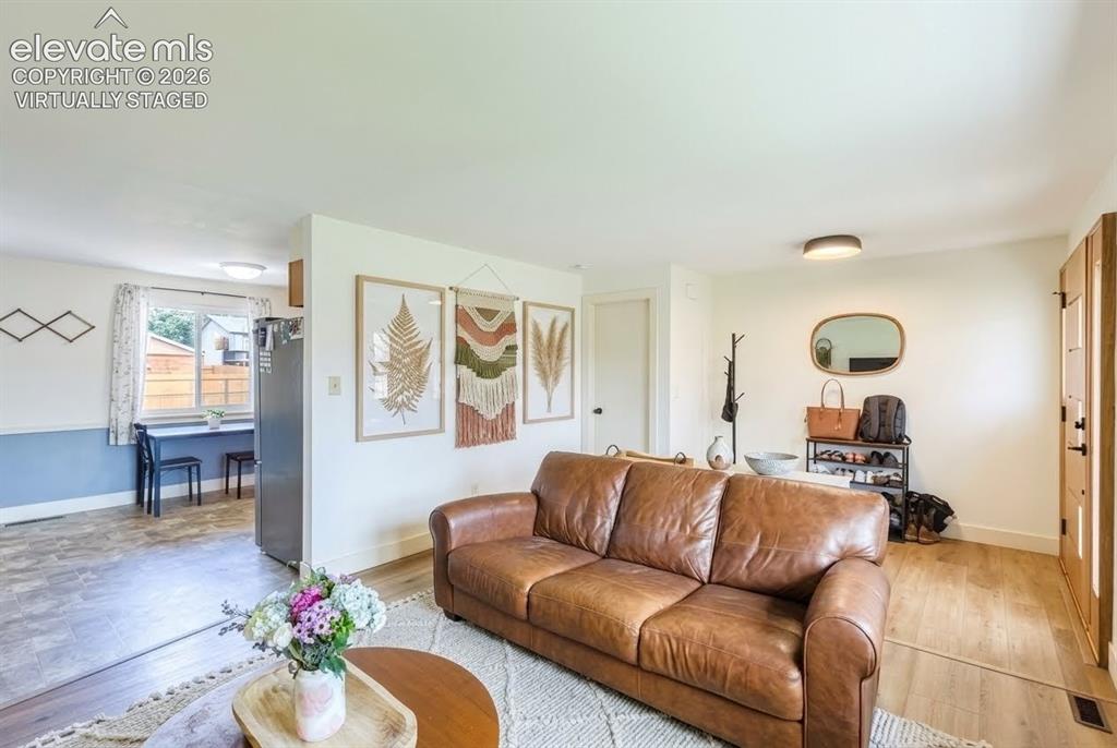 Image 5 of 49: Living area featuring light wood-finish flooring, white walls, and a promin