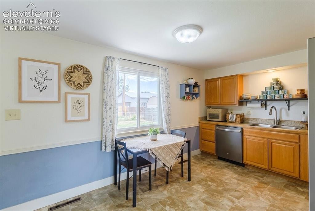 Image 8 of 49: Compact kitchen featuring wood-finish cabinetry, a stainless steel dishwash