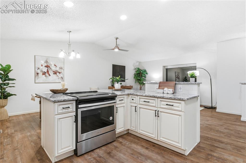 Image 11 of 31: Kitchen with stainless steel electric range oven, light stone countertops,