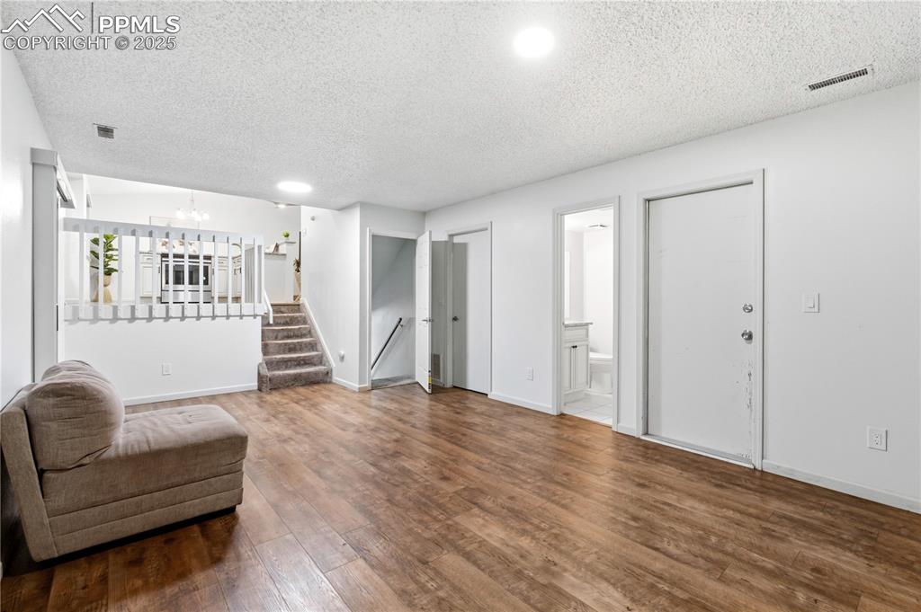 Image 19 of 31: Living area with wood finished floors, a textured ceiling, stairway, and a