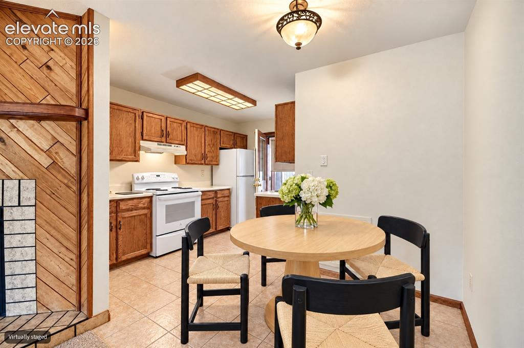 Image 11 of 23: Kitchen featuring wood cabinetry, integrated white appliances, and a tiled