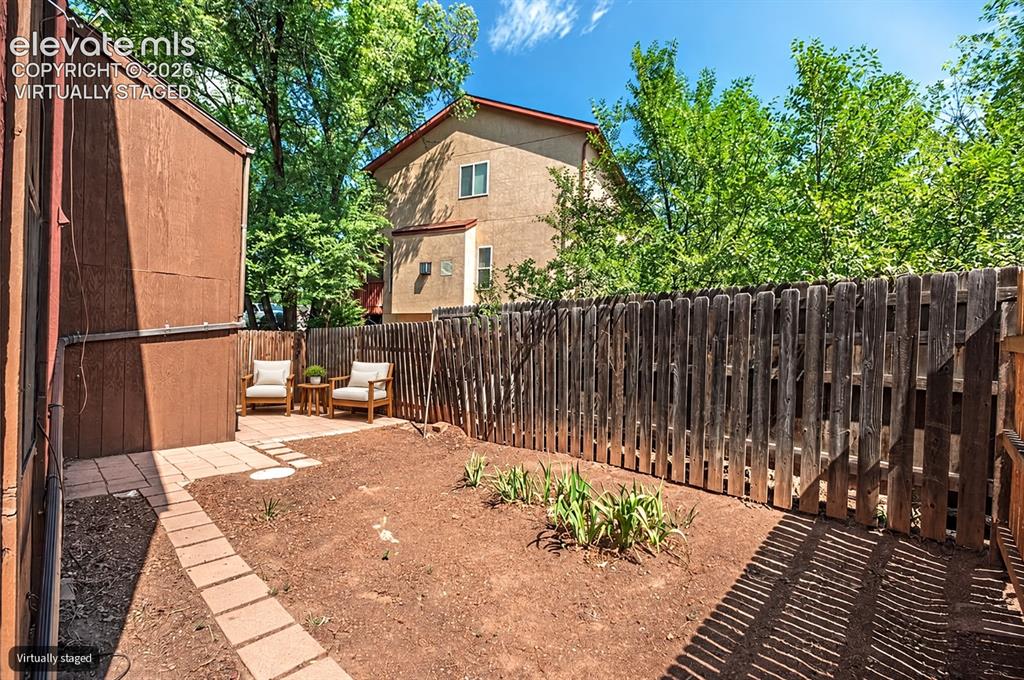 Image 21 of 23: Virtually Staged Paved patio area, wood fencing, and established ground cov