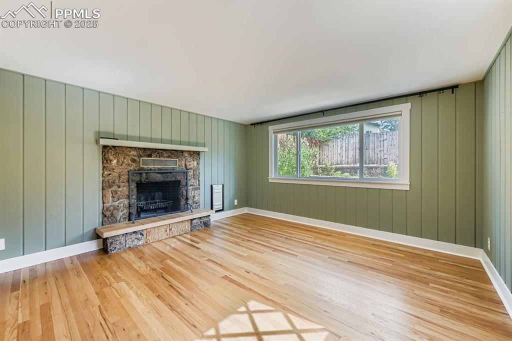 Image 10 of 28: Unfurnished living room with a fireplace, light wood-type flooring, and woo