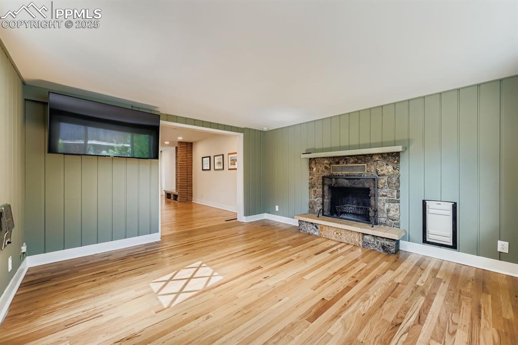 Image 12 of 28: Unfurnished living room with a stone fireplace, light wood finished floors,