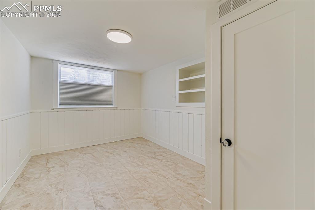 Image 21 of 28: Unfurnished room with built in features and wainscoting