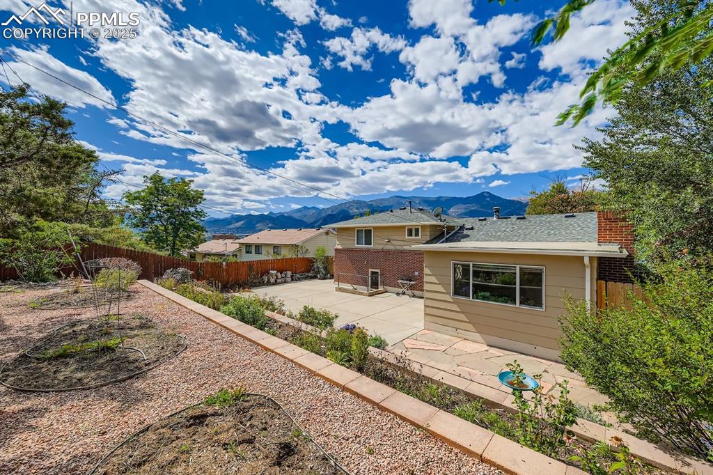 Image 23 of 28: Back of property with a patio area, a mountain view, a fenced backyard, bri