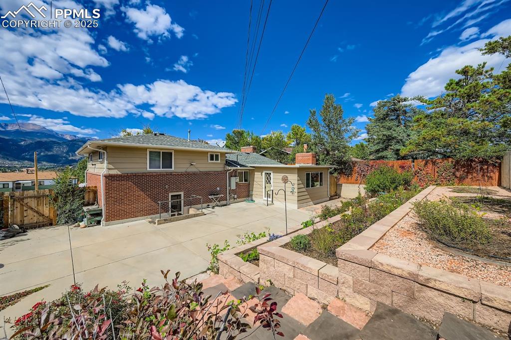 Image 26 of 28: Rear view of house featuring brick siding, a fenced backyard, and a patio a