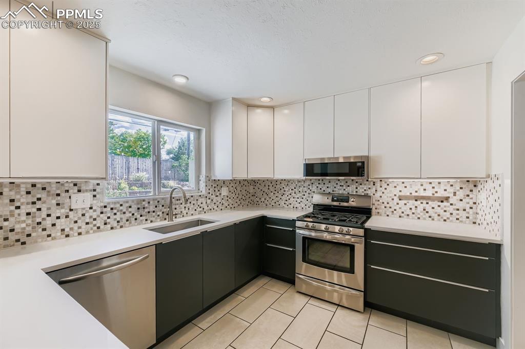 Image 3 of 28: Kitchen featuring modern cabinets, white cabinetry, appliances with stainle