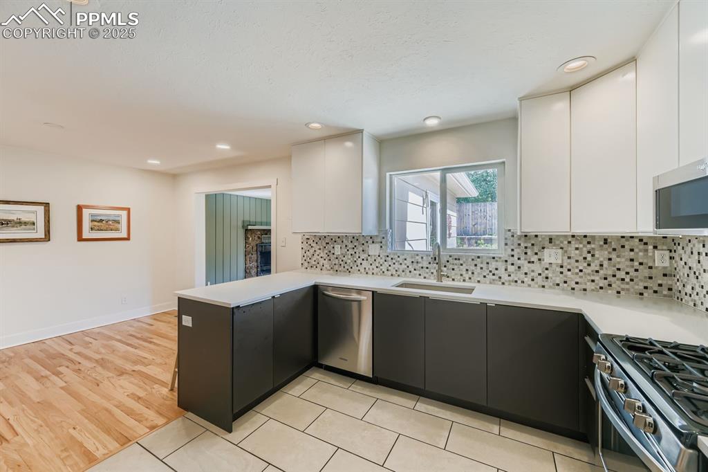 Image 4 of 28: Kitchen with modern cabinets, white cabinets, a peninsula, and recessed lig