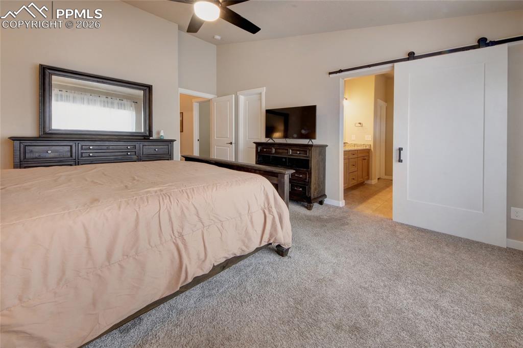 Image 14 of 36: Master bedroom with barn door entry to bathroom