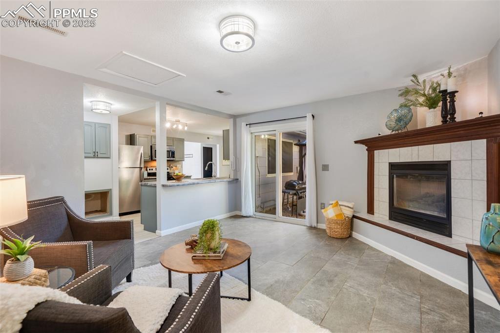 Image 13 of 23: Living room with a tile fireplace and attic access
