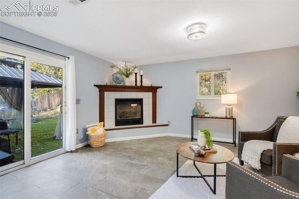 Image 14 of 23: Sitting room with a tile fireplace and stone finish flooring