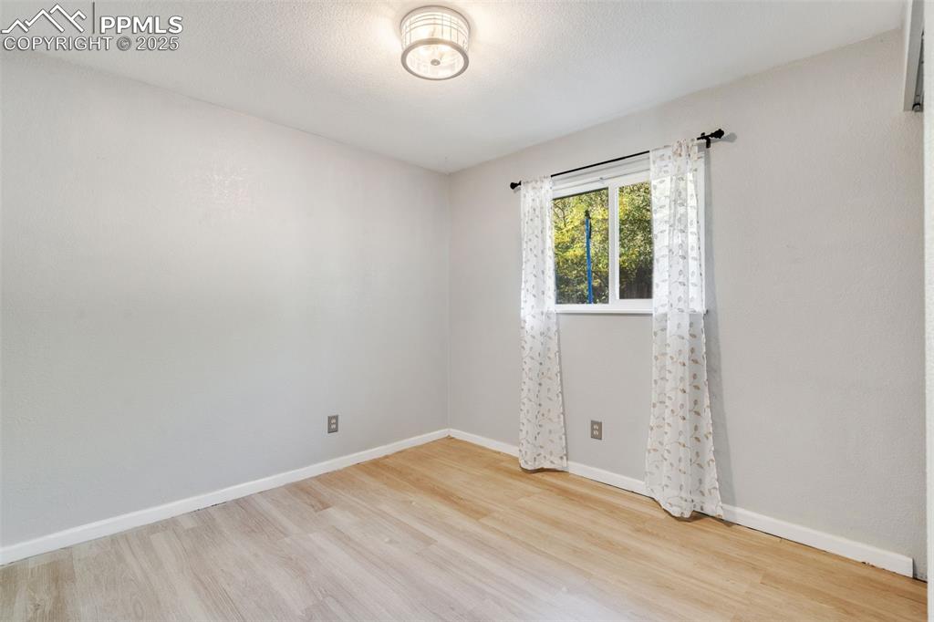 Image 20 of 23: Empty room featuring light wood-type flooring and a textured ceiling