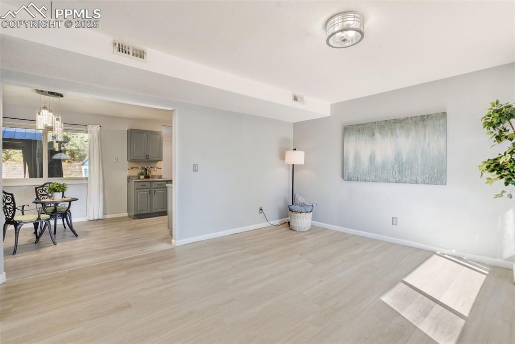 Image 4 of 23: Unfurnished living room featuring light wood-type flooring and a chandelier