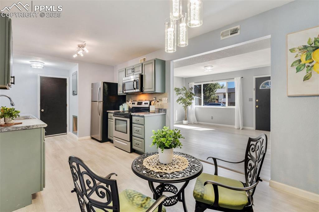 Image 7 of 23: Kitchen with green cabinetry, appliances with stainless steel finishes, lig