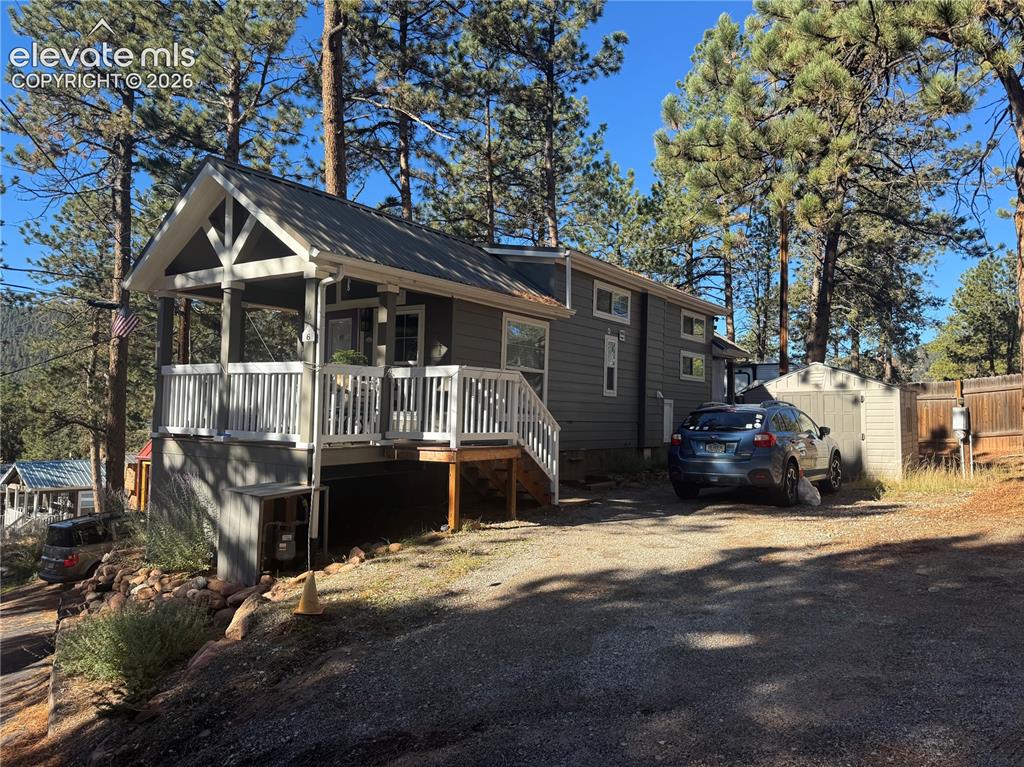 Caption: Exterior featuring horizontal siding, a covered front porch with white railing, a metal roof, and a 