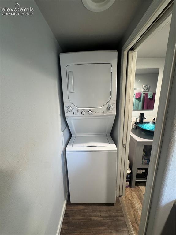 Image 11 of 12: Stacked washer and dryer unit with white finish, wood-finish flooring, grey