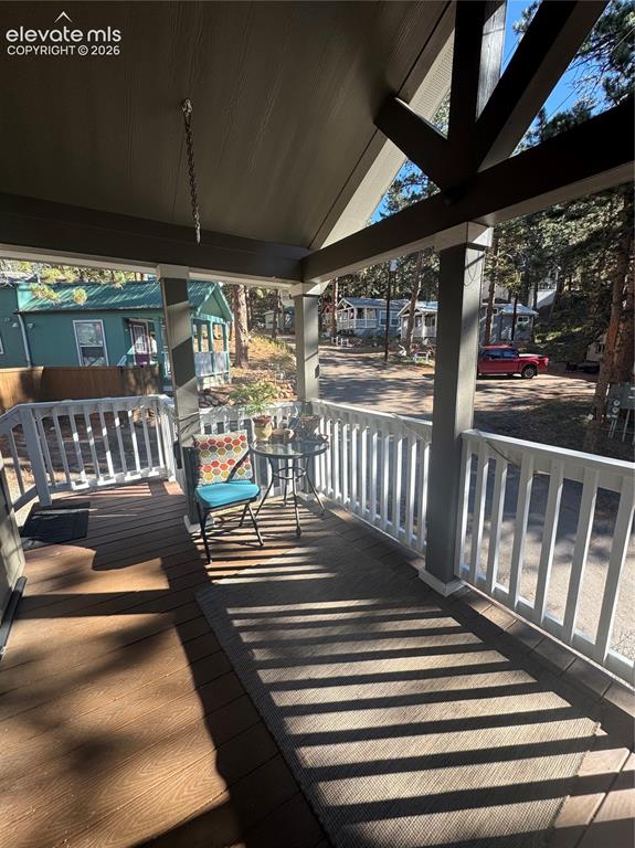 Image 2 of 12: Covered front porch featuring exposed wood vaulted ceiling beams, wood-fini