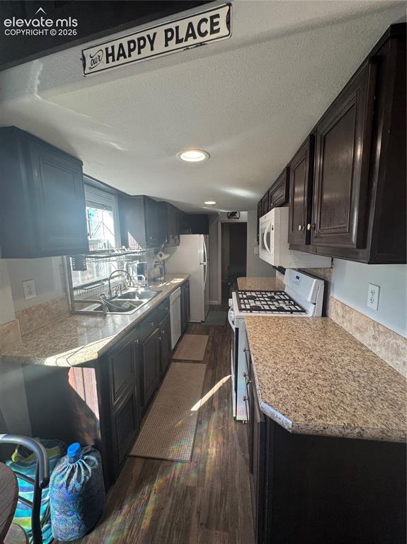 Image 3 of 12: Galley-style kitchen featuring dark-stained cabinetry, stone-finish counter