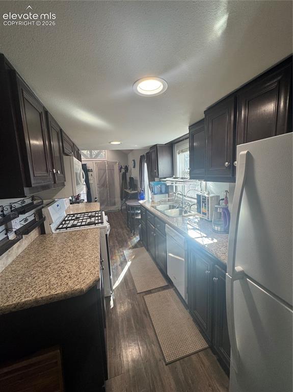 Image 4 of 12: Kitchen featuring dark wood cabinetry, stone-surface countertops, recessed 