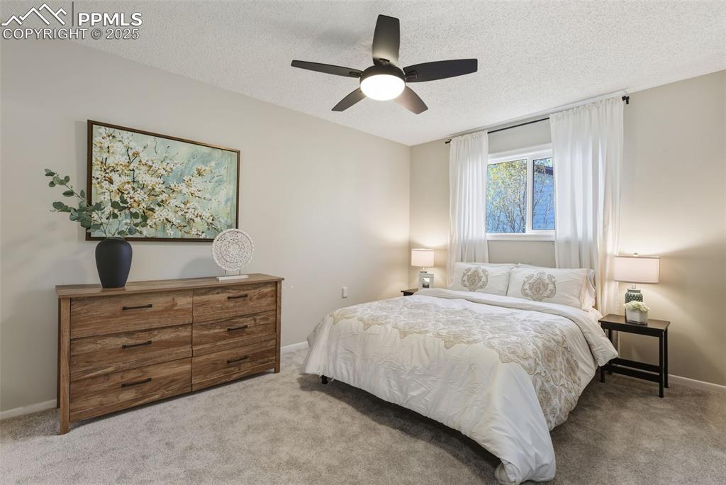 Image 10 of 34: Bedroom featuring carpet floors, a textured ceiling, and a ceiling fan