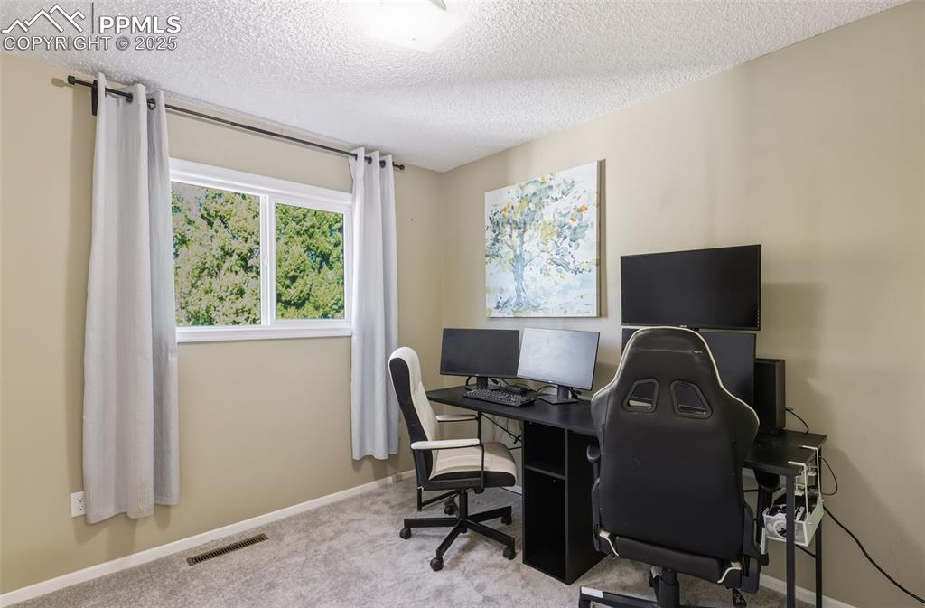 Image 15 of 34: Carpeted home office/bedroom featuring a textured ceiling and baseboards