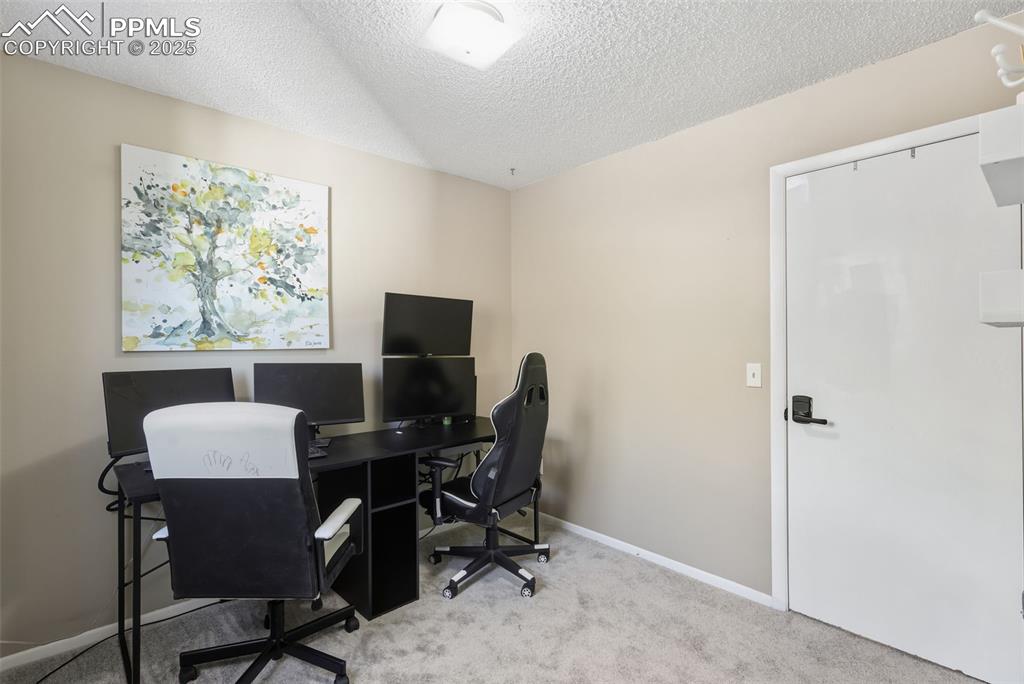 Image 16 of 34: Carpeted home office with a textured ceiling and baseboards