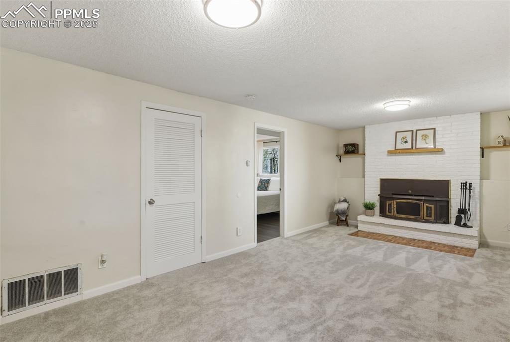 Image 18 of 34: Unfurnished living room featuring a textured ceiling, carpet floors, and a 