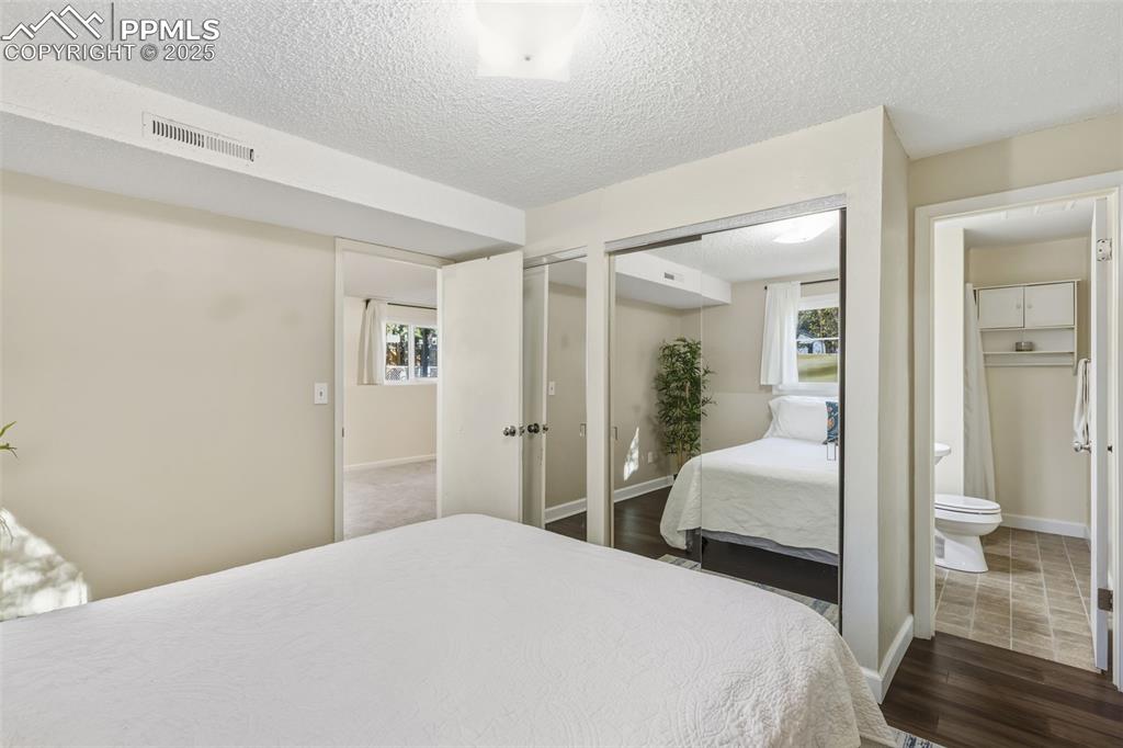 Image 20 of 34: Bedroom featuring a textured ceiling, dark wood-style floors, and two close