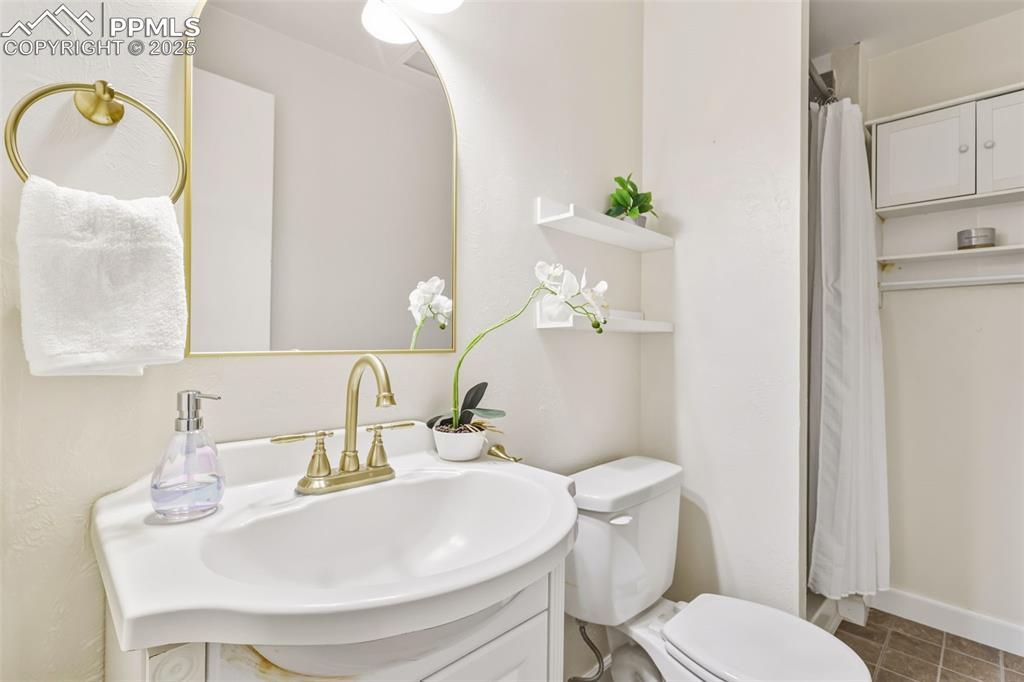 Image 21 of 34: Bathroom with vanity, curtained shower, and dark tile patterned flooring