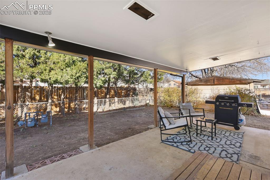 Image 24 of 34: Fenced backyard featuring a patio, a grill, and outdoor dining space