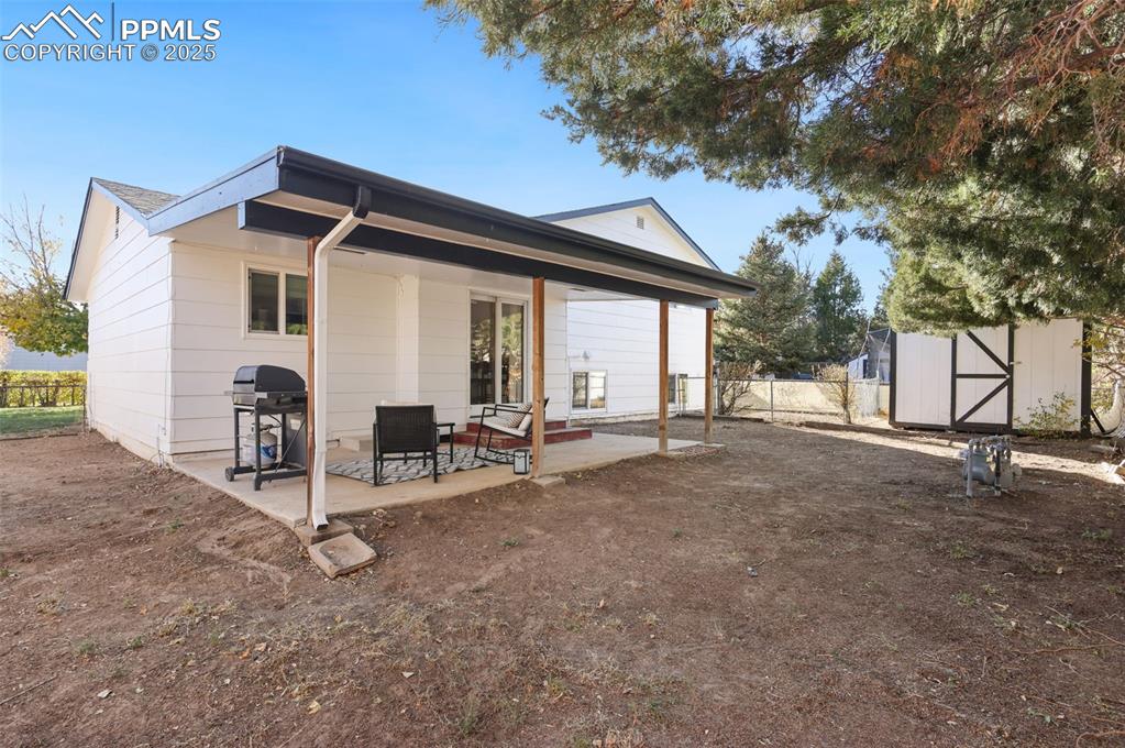 Image 25 of 34: Back of property with a storage shed and rear covered patio