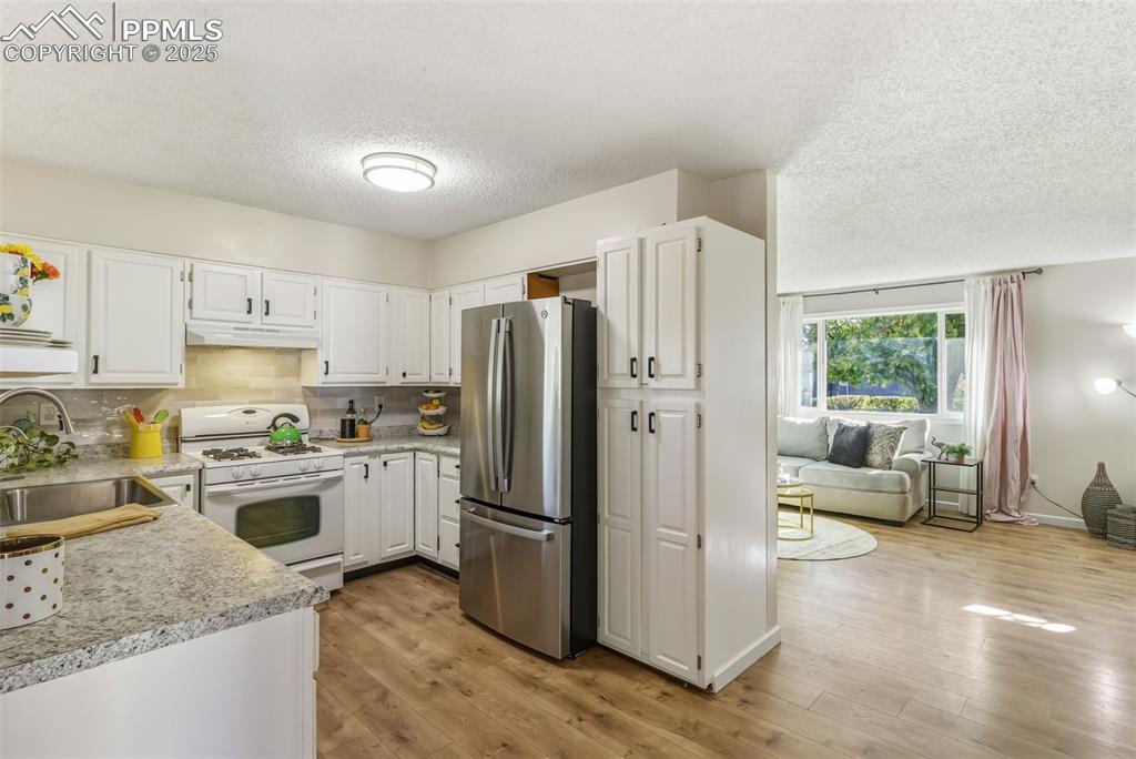 Image 5 of 34: Kitchen featuring white cabinets, white range with gas stovetop, freestandi