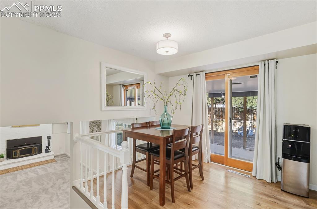 Image 6 of 34: Dining room with a fireplace with raised hearth, light wood-type flooring, 