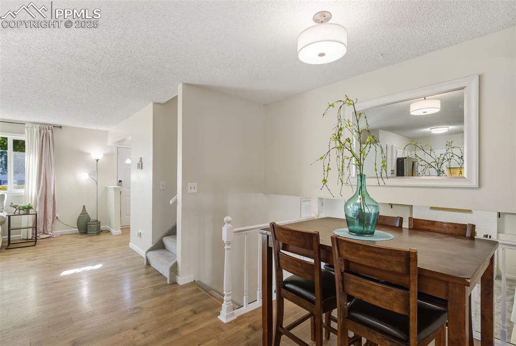 Image 8 of 34: Dining room with light wood-style flooring, a textured ceiling, and stairwa
