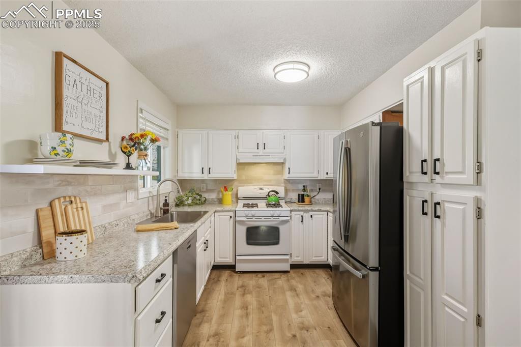 Image 9 of 34: Kitchen with stainless steel appliances, a textured ceiling, white cabinets