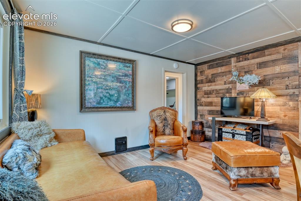 Image 15 of 47: Relax here in the living space featuring a wood-panel accent wall, light wo