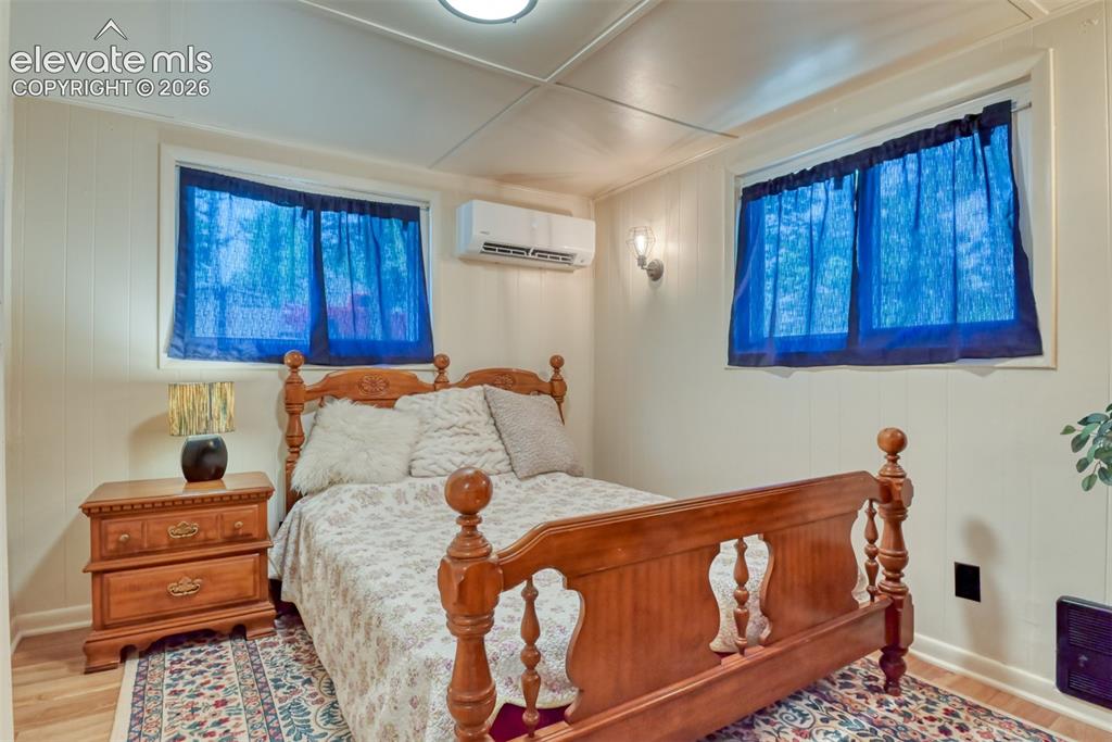 Image 20 of 47: Bedroom featuring two windows with blue privacy curtains, white paneling, w