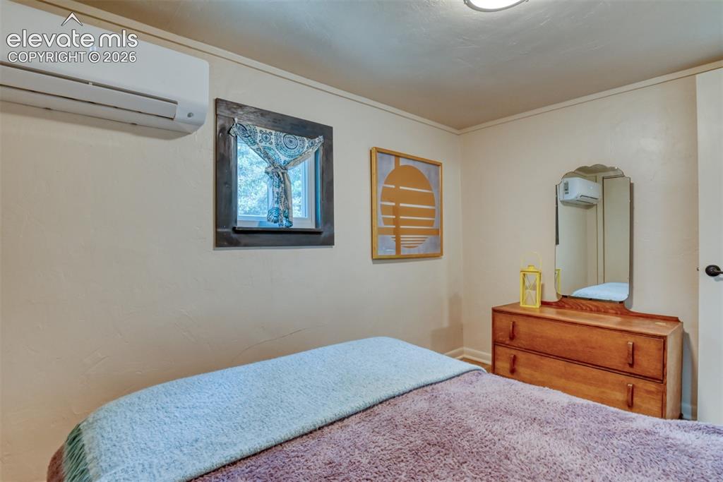 Image 29 of 47: Bedroom with a window featuring dark trim, a wall-mounted mini-split HVAC u