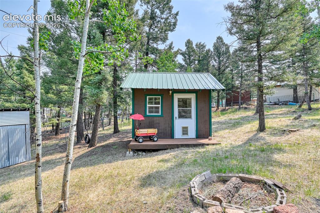 Image 30 of 47: Extra cabin with green metal roof, a wood-finish exterior, and porch