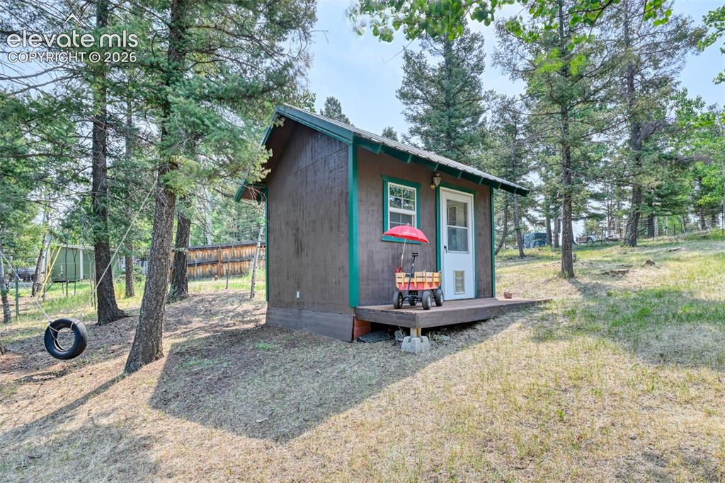 Image 31 of 47: Compact cabin structure featuring brown siding with green trim, a white ent