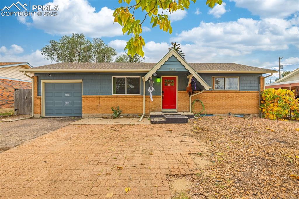 Caption: View of front of property featuring asphalt driveway, a shingled roof, a garage, and brick siding