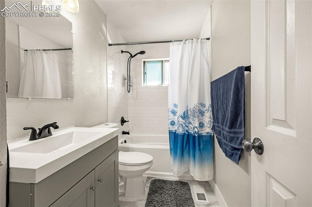 Image 12 of 37: Full bathroom featuring a textured wall, shower / bath combo, and vanity