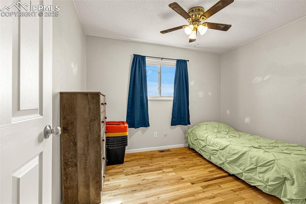 Image 13 of 37: Bedroom with light wood-type flooring, ceiling fan, and a textured ceiling