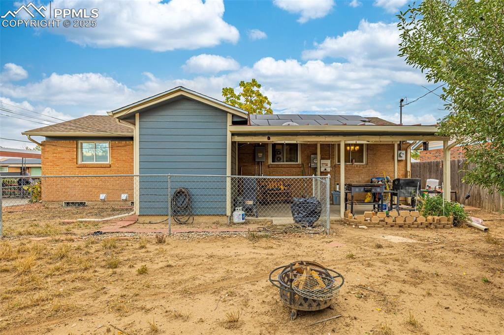 Image 23 of 37: Back of house featuring a fire pit, brick siding, a fenced backyard, solar