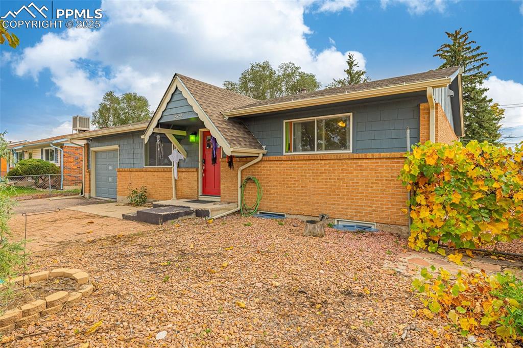 Image 3 of 37: View of front facade with a garage, a shingled roof, and brick siding