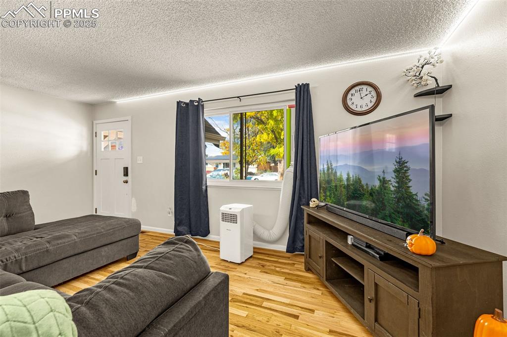Image 5 of 37: Living area featuring light wood-type flooring and a textured ceiling